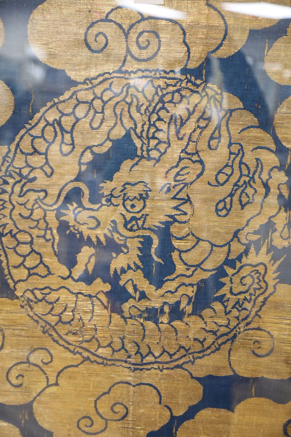 A Chinese gold thread embroidered panel, depicting celestial dragons amongst stylised clouds